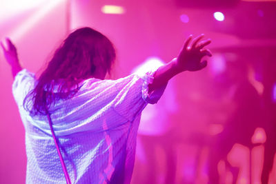 Rear view of woman dancing against illuminated lights