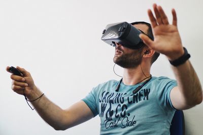 Mid adult man using virtual reality simulator while sitting on chair