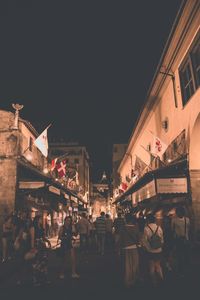 People in city against sky at night