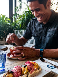 Close-up of smiling man eating food on table