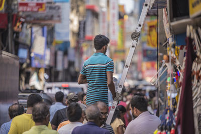 Rear view of people walking on street in city