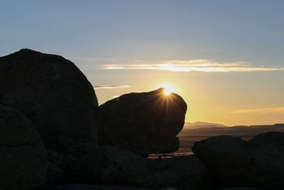 Rock formation by sea against sky during sunset