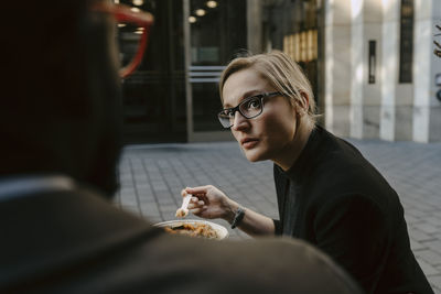 Female entrepreneur discussing with male colleague while having salad on footpath