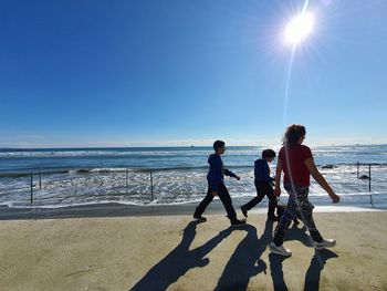 People on beach against sky during sunny day