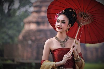 Smiling young woman in traditional clothing standing outdoors