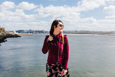 Young woman standing by sea against sky