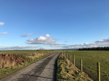 Road amidst field against sky