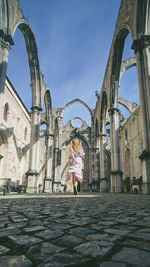 Rear view of woman standing by buildings against sky