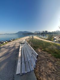 Road by lake against clear blue sky