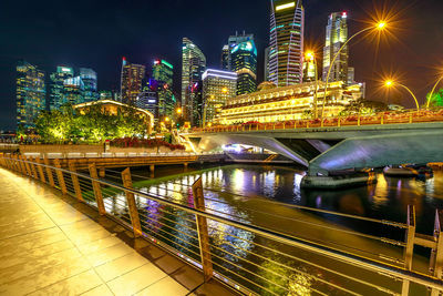 Illuminated bridge over river amidst buildings in city at night