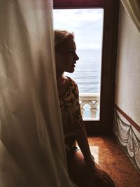 Young woman sitting against window in cruise ship