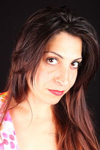 Close-up portrait of smiling young woman against black background