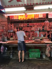 Rear view of a butcher selling meat