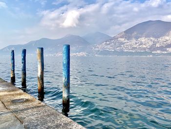 Wooden posts in lake against mountains