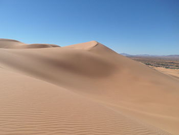 Sand dunes in desert against clear sky