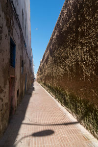Narrow alley amidst buildings against sky on sunny day
