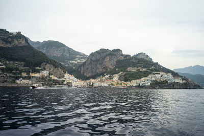 Scenic view of sea by mountains against sky