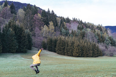 Rear view of man jumping on grassy field