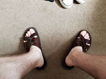 Low section of man wearing flip flop at home