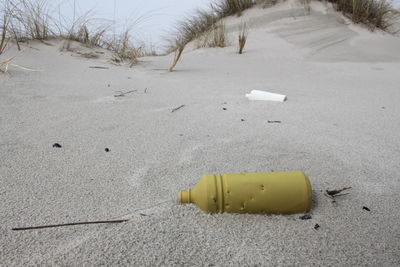 High angle view of abandoned yellow bottle on sand