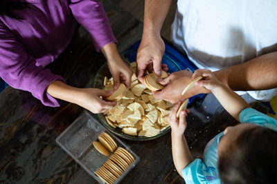 Hands making malaysian triple chocolate dessert.  crushing the cookies into tiny pieces.