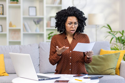 Young woman using laptop while sitting on table