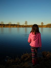 Rear view of man standing in lake against clear sky