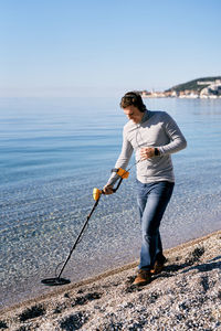 Full length of man standing on beach against sky