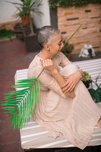 Side view of young woman sitting on table