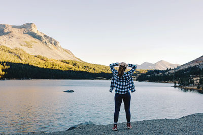 Woman standing near the peaceful lake, view from the back. relaxing outdoors