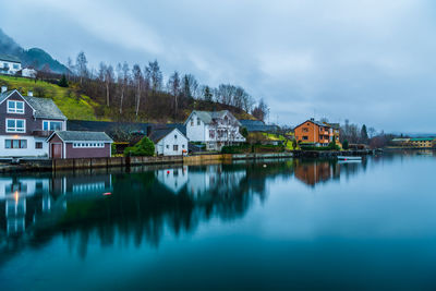 Reflection of houses and buildings in lake against sky