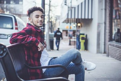Portrait of smiling young man sitting in city