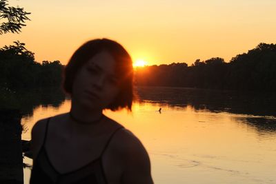 Portrait of silhouette woman by lake against sky during sunset