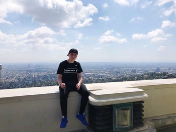 Portrait of young man in city against sky