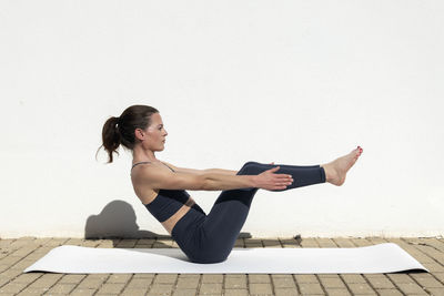 Portrait of young woman exercising against clear sky