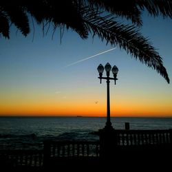 Silhouette people by sea against clear sky during sunset