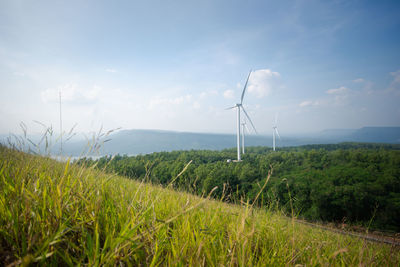 Wind turbines on field against sky