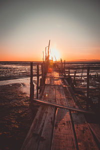 Pier over sea against sky during sunset