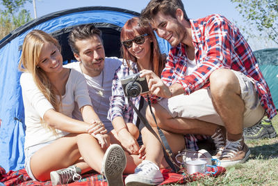 Friends using phone while sitting on picnic