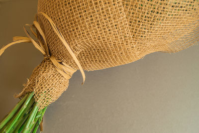 Example of packing a bouquet of flowers in a brown floral grid, close-up on a gray background.