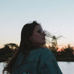 Woman with tousled hair against sky