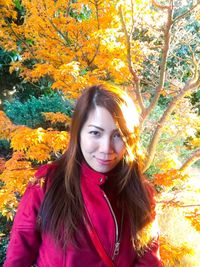 Portrait of young woman standing in park during autumn