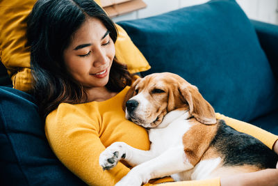 Portrait of woman with dog sitting on sofa at home