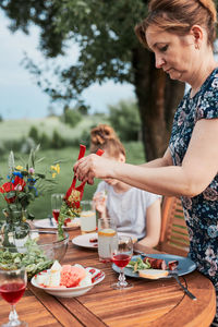 Woman having a meal from grill during summer family picnic outdoor dinner in a home garden