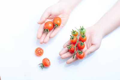 Cropped image of hand holding strawberry over white background