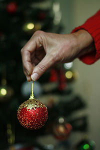 Cropped image of person celebrating christmas tree