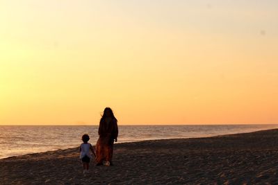 Rear view of women on beach during sunset