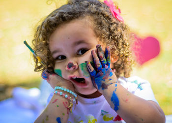 Portrait of cute girl with paint on hand and face