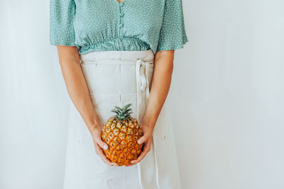Midsection of a woman holding pineapple in front of her