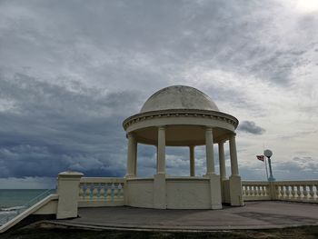 Gazebo at beach against cloudy sky